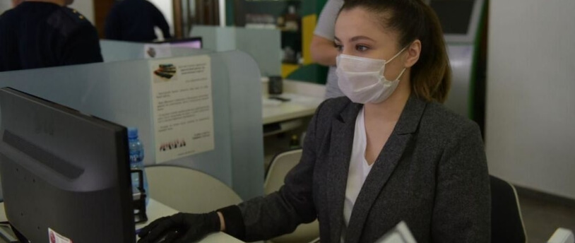 девушка в медицинской маске работает за компьютером