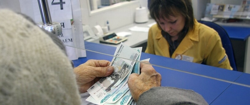 пожилая женщина расплачивается в кассе банка