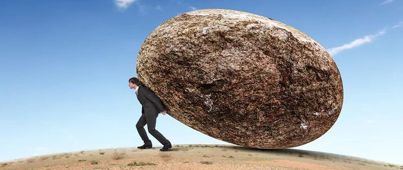 мужчина пытается удержать огромный камень