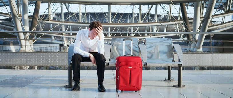 расстроенный турист с чемоданом в аэропорту