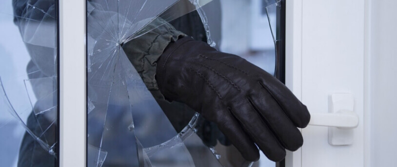 рука преступника, разбившего стекло входной двери