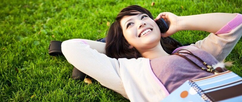 девушка лежит на лужайке и разговаривает по телефону