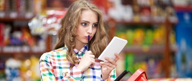 девушка в супермаркете с корзиной и со списком покупок в руках 