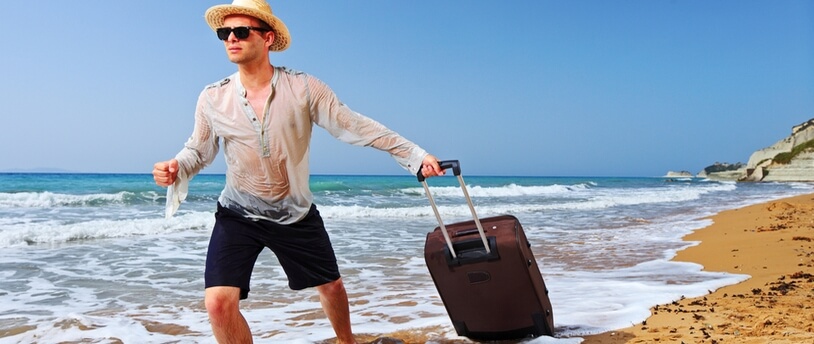 мужчина-турист с чемоданом бежит по берегу моря
