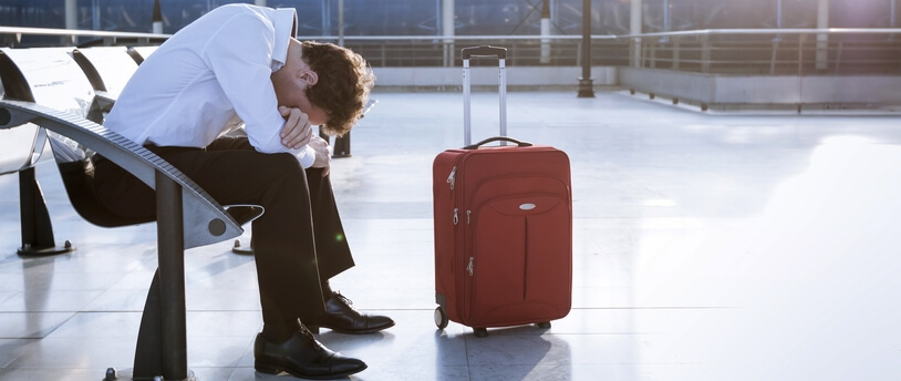 уснувший в аэропорту путешественник с чемоданом