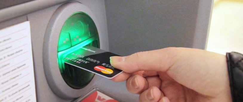 человек использует пластиковую карту в банкомате