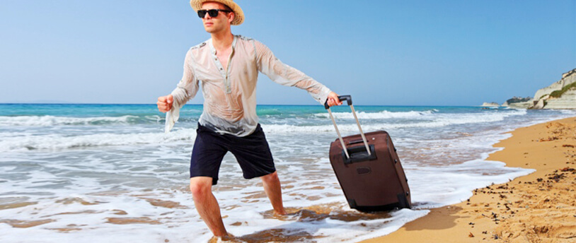 мужчина с чемоданом идет по берегу моря
