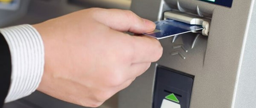 человек вставляет карту в банкомат