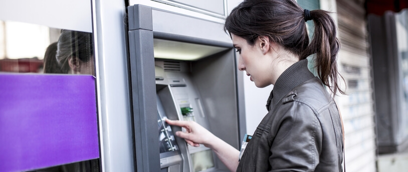 девушка пользуется банкоматом