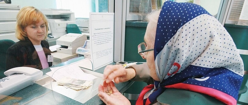 пожилая женщина расплачивается в кассе