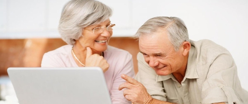 два пенсионера сидят за ноутбуком