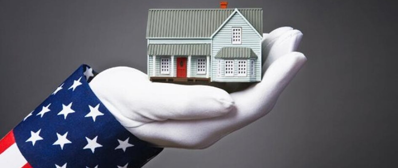 рука "в костюме американского флага" держит макет дома