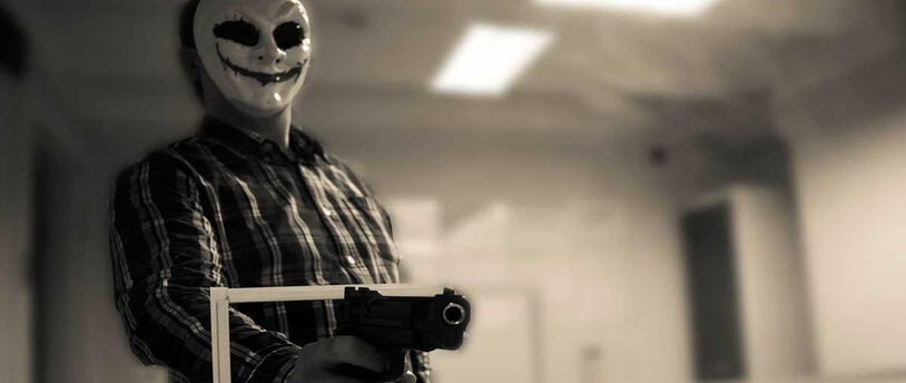 преступник в маске угрожает пистолетом