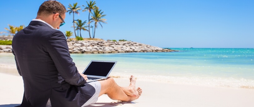 человек в костюме с ноутбуком на пляже